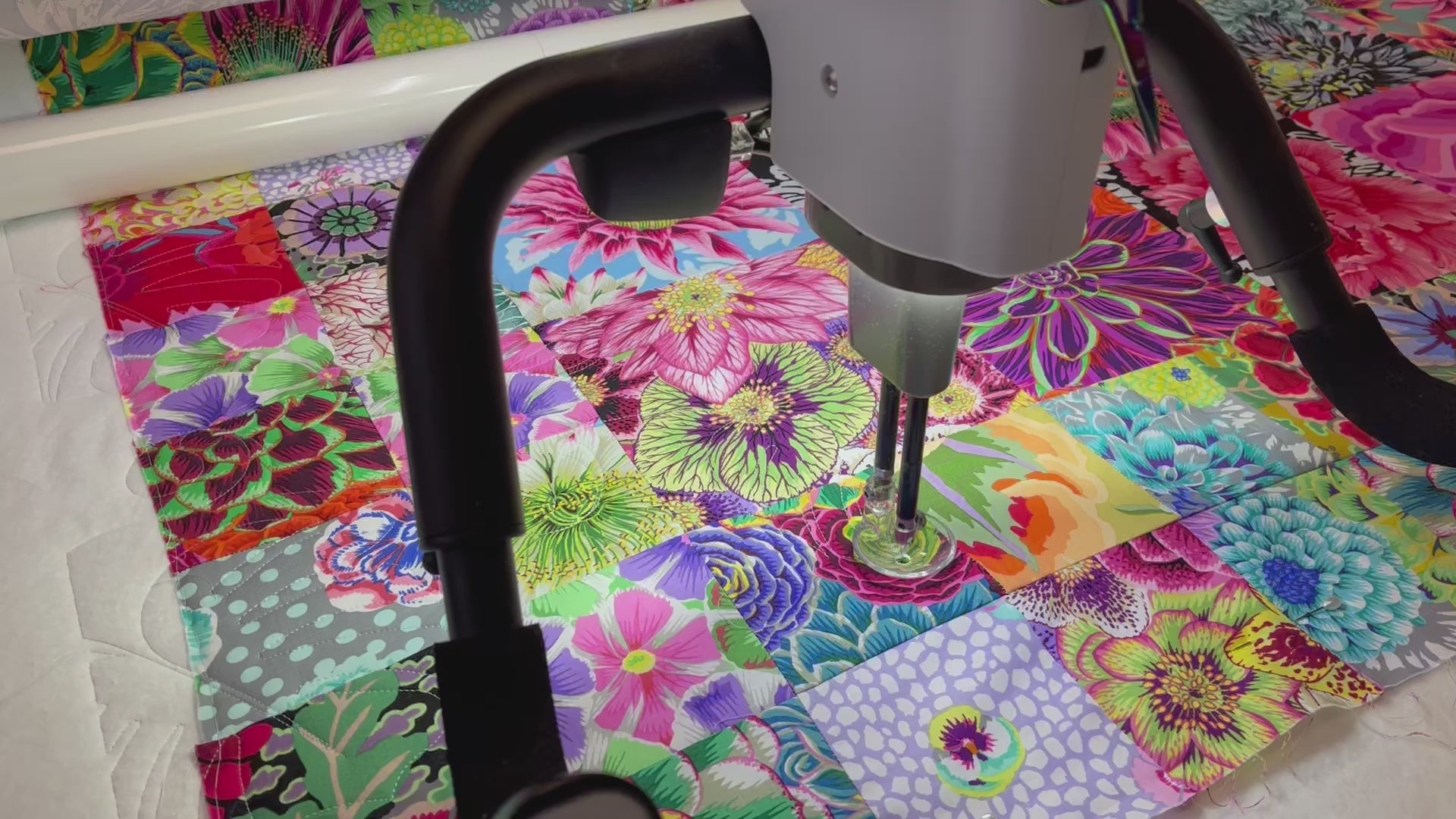 Load video: TheFatQuarter longarm machine quilting a Kaffe Fassett quilt top with a edge-to-edge large cheese plant leaf design